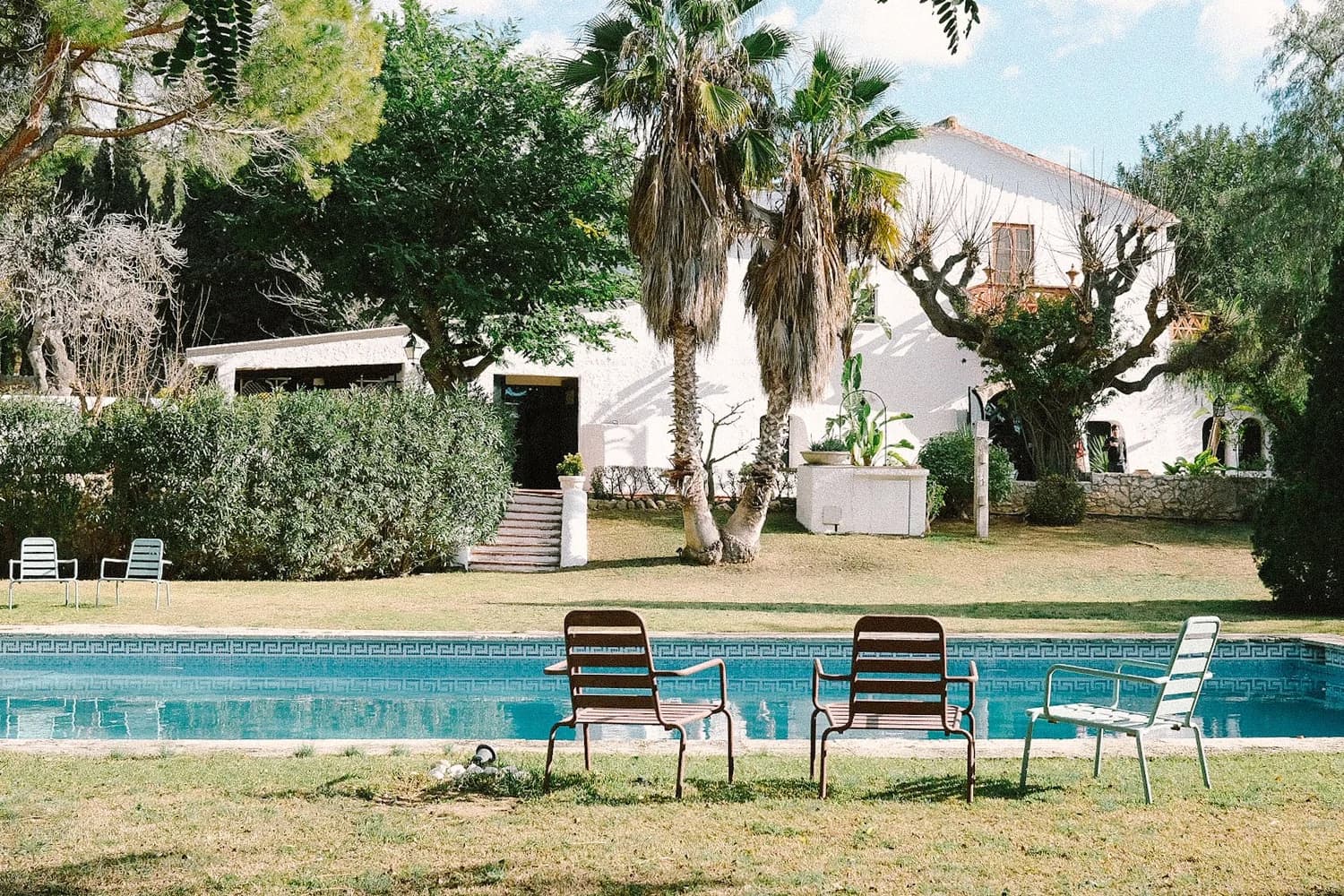 La pool house encalada rodeada de un jardín exuberante